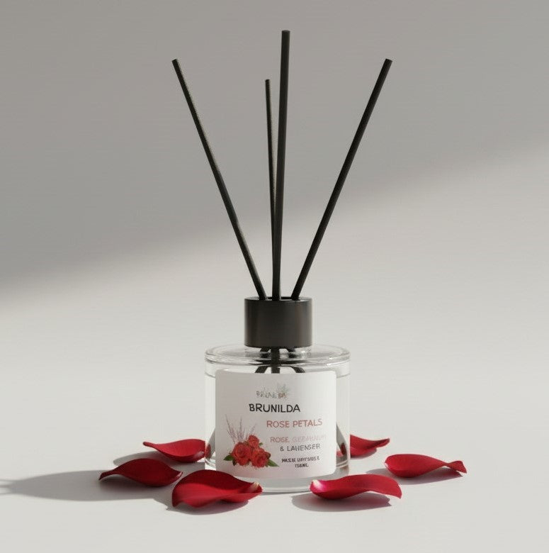 Diffuser with black sticks and red flower petals on a light gray background